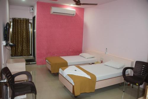 a room with two beds and a pink wall at Hotel Uma Executive Lodging in Nānded