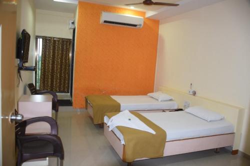 a hotel room with two beds and a tv at Hotel Uma Executive Lodging in Nānded