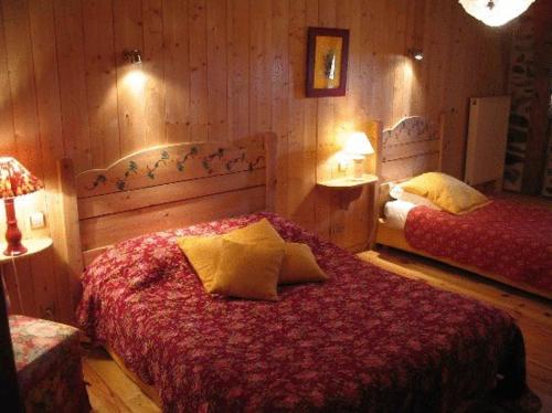 a bedroom with two beds in a room with wooden walls at Le Francillon in Les Estables