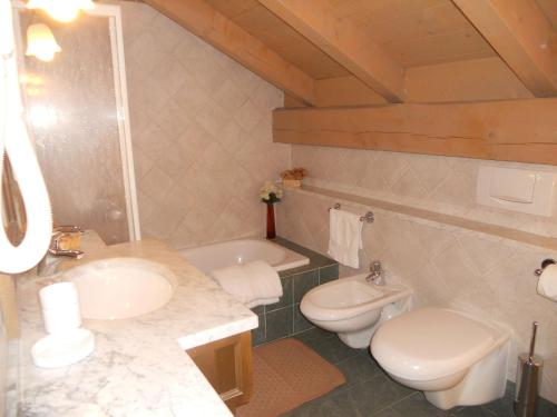 a bathroom with a sink and a toilet and a tub at Residence Villa Avisio in Canazei