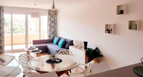a living room with a glass table and chairs at Spacious luxe apartment on Mar Menor Golf Resort with Padel, Fitness, Wellness facilities in Torre-Pacheco