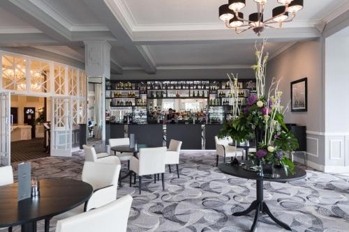 a restaurant with tables and chairs and a bar at The Carlyon Bay Hotel and Spa in St Austell