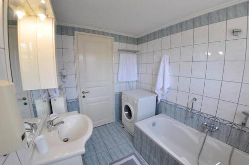 a bathroom with a tub and a sink and a washing machine at Villa Leo Junior in Áno Korakiána