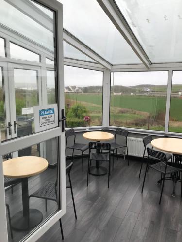 a room with tables and chairs and windows at Finn McCools Giants Causeway Hostel in Bushmills