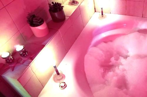 une salle de bains rose avec une baignoire rose et des nuages. dans l'établissement אוויר הרים, à Kefar Weradim