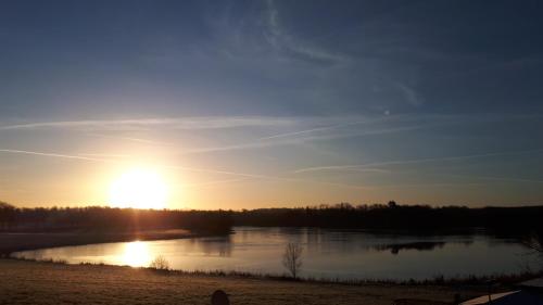 una puesta de sol sobre un lago con la puesta de sol en Dachgeschosswohnung mit Seeblick, en Ahrensbök