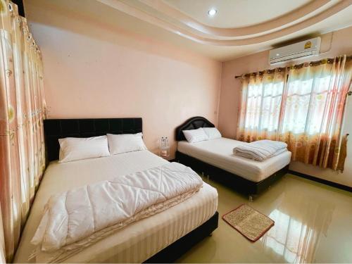 a bedroom with two beds and two windows at เกาะลิบงซันไรส์ โฮมสเตย์ Koh libong sunrise Homestay in Ko Libong