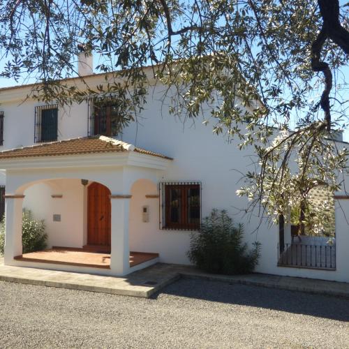 a white house with a door and a tree at Cortijo Rocas Altas in Iznájar