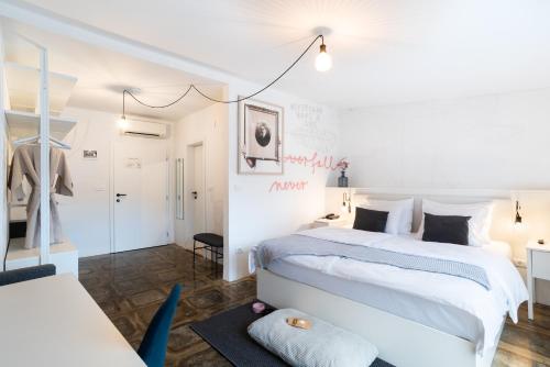 a white bedroom with a large bed and a chair at Art Hotel Tartini in Piran
