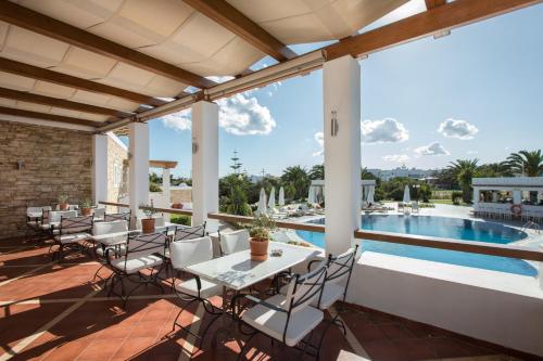 een patio met een tafel en stoelen en een zwembad bij Porto Naxos in Naxos Chora