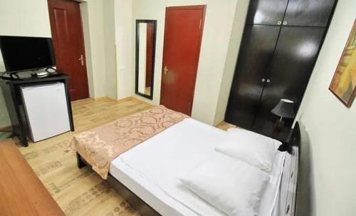 1 dormitorio con 1 cama blanca y TV en Almeto Hotel, en Tiflis