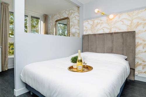 sypialnia z białym łóżkiem i tacą z butelkami wina w obiekcie Le Lac d'Or - Duke Housing w mieście Créteil
