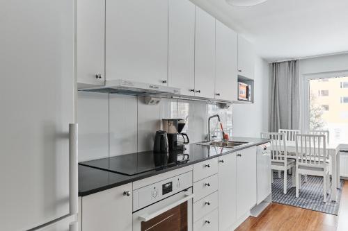 a kitchen with white cabinets and a black counter top at Continental Apartment Hotel Knivsta in Knivsta