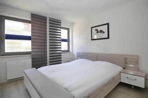 ein weißes Schlafzimmer mit einem Bett und einem Fenster in der Unterkunft Hanse-Haus Wohnung 04 in Boltenhagen