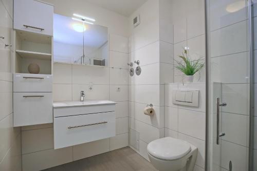 ein weißes Badezimmer mit Toilette und Waschbecken in der Unterkunft Hanse-Haus Wohnung 04 in Boltenhagen