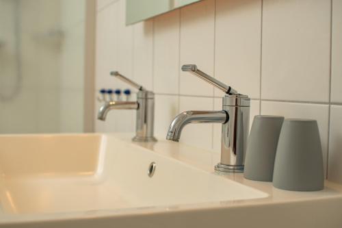 a bathroom sink with two faucets and two cups at Het Klooster van Dalfsen in Dalfsen
