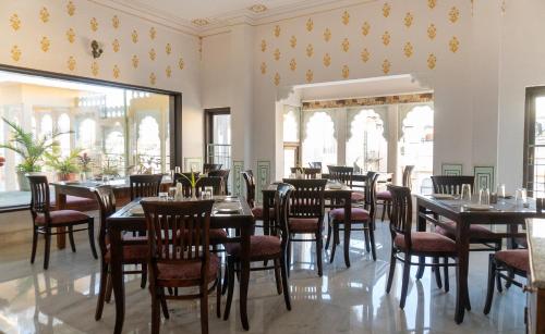 a dining room with tables and chairs and windows at Amar Kothi in Udaipur