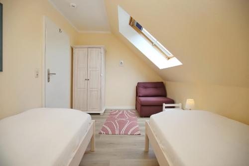 Cette chambre comprend deux lits et un fauteuil rouge. dans l'établissement Feriendorf Papillon Wohnung 08-7, à Boltenhagen
