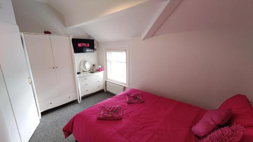 a bedroom with a bed with pink sheets and a window at The Castleton in Blackpool