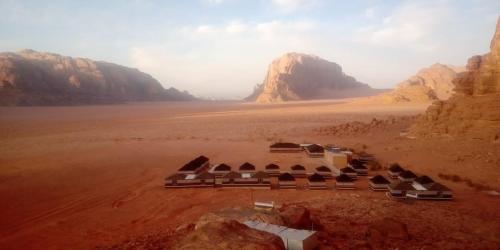 a building in the middle of a desert with mountains at Wadi Rum Quiet Village Camp in Wadi Rum