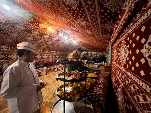 a chef standing in front of a buffet line with food at Wadi Rum Quiet Village Camp in Wadi Rum