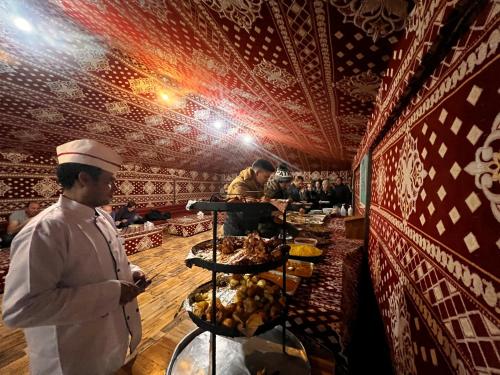 um chef em frente a uma fila de buffet com comida em Wadi Rum Quiet Village Camp em Wadi Rum