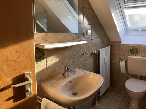 bagno con lavandino, servizi igienici e specchio di Ferienwohnung bei Fredy a Langenargen