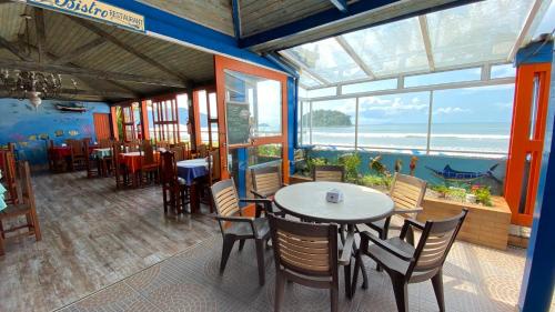a restaurant with tables and chairs and a view of the ocean at Kaliman Pousada in Ubatuba