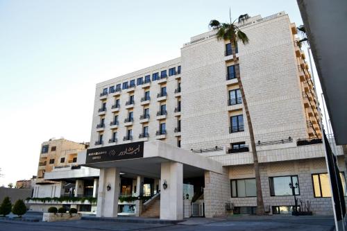 a building with a palm tree in front of it at Ambassador, a Boutique Hotel in Amman