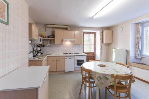 eine Küche mit einem Tisch und Stühlen sowie einem Kühlschrank in der Unterkunft Gîte de la Charrière in Montboillon