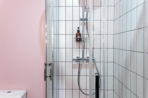 La salle de bains est pourvue d'une douche et de murs en carrelage blanc. dans l'établissement The New Bliss - Duke Housing, à Vitry-sur-Seine