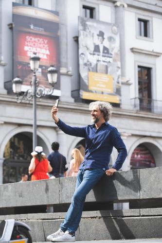 a man leaning on a wall while holding a cell phone at Ocean Drive Madrid in Madrid