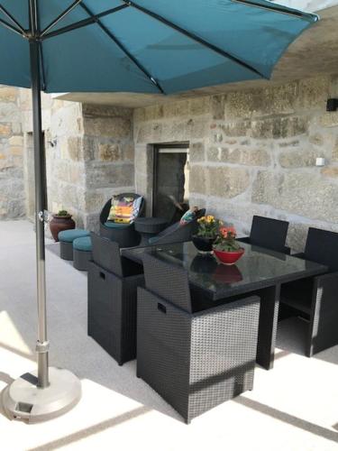 a table and chairs with a blue umbrella at Casa d'Amares in Amares