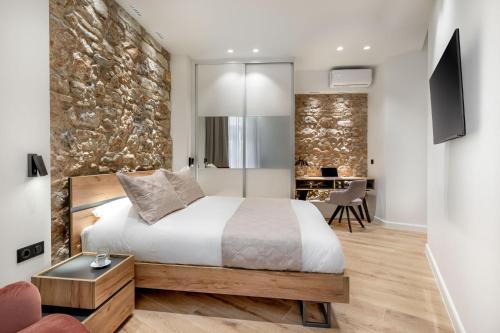 sypialnia z łóżkiem i kamienną ścianą w obiekcie J&A Luxury Residence w Atenach