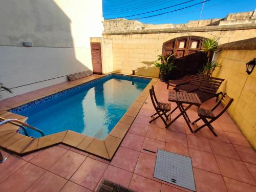 een zwembad met stoelen en een tafel op een patio bij Grotto's Paradise B&B in Għarb