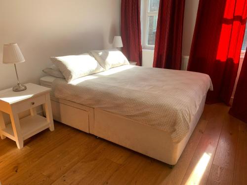 a bed in a bedroom with red curtains and a table at Farriers House in London