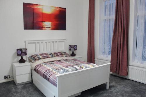 a bedroom with a white bed and two lamps on tables at 2 bed 1st floor Apartment-own entrance & parking in Portsmouth