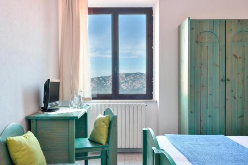 a room with a desk with a computer and a window at S'Enis Monte Maccione in Oliena