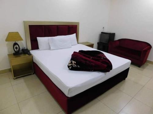 sypialnia z dużym łóżkiem i czerwonym krzesłem w obiekcie Royal Castle w Rahimjar Khan