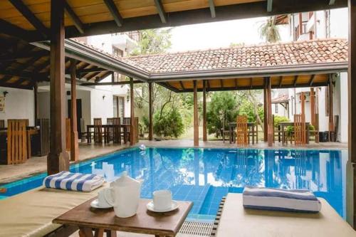 a pool with a table and chairs and a house at Lagoon Boutique Hotel in Tangalle