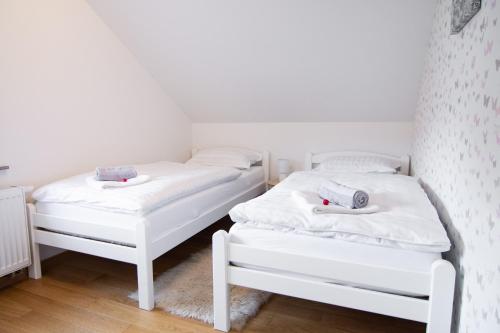 2 weiße Betten in einem Zimmer mit weißen Wänden in der Unterkunft Apartma Tia in Zreče