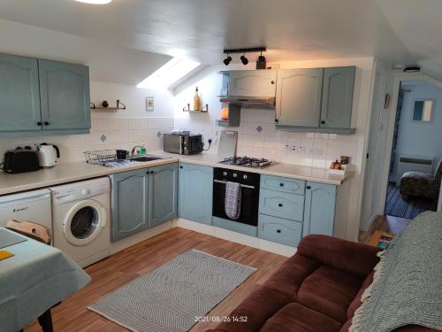 a kitchen with blue cabinets and a stove top oven at Stromness Apartments in Stromness
