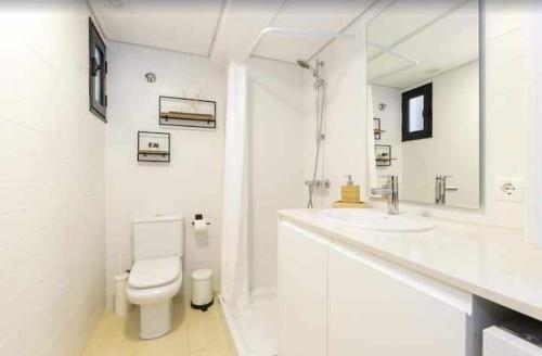 a white bathroom with a toilet and a sink at Maravilloso apto de diseño a 1 minuto de la playa in Cala Santandria