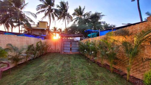 a backyard with a brick wall and palm trees at Hostel Mandala in Anjuna