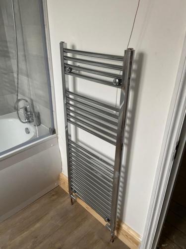 a bathroom with a metal radiator next to a bath tub at Lovely, recently refurbished four bedroom house.. in Hither Green
