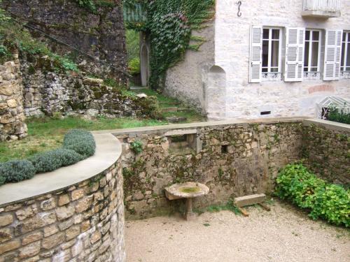 a stone wall with a bench in front of a building at Au fil de l'eau in Cerdon