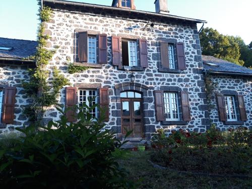 an old stone house with brown shutters at La Grange de Lily in Vic-sur-Cère