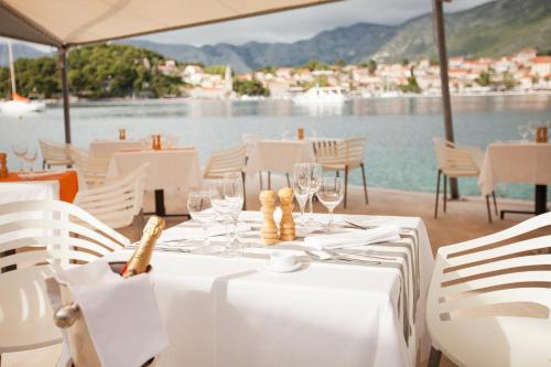 a white table with wine glasses and a view of the water at Hotel Croatia in Cavtat