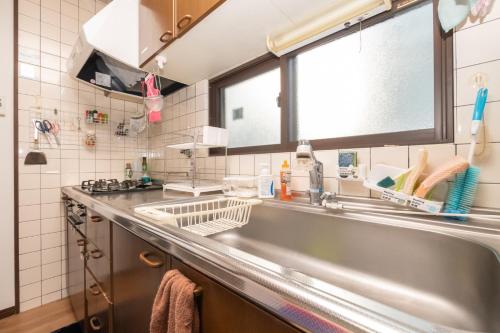 a kitchen with a stainless steel sink and a window at ゲストハウスOneWorld Toji東寺 in Kyoto