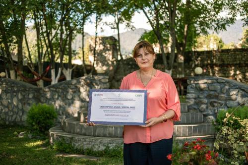a woman is holding a sign in a garden at Family Hotel Lago & Wine Cellar in Lagodekhi